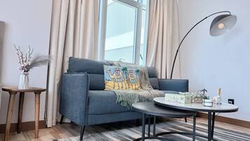 A modern living room with a sofa, a round coffee table, a lamp, and a decorative vase.