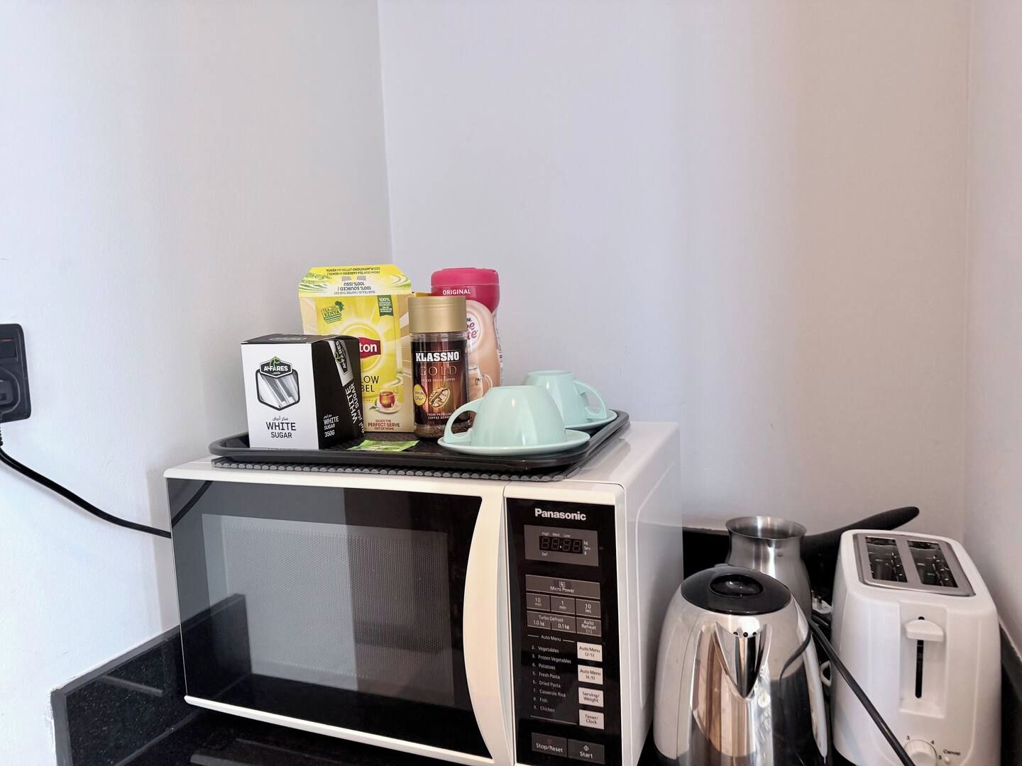 A microwave with a tray of food items and a toaster on a countertop.