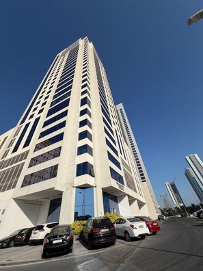 Ein hohes, modernes Gebäude mit einem markanten Eingang und einem Parkplatz davor.