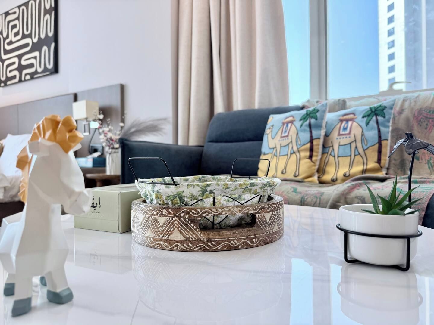 En moderne stue med sofa, pyntepuder, sofabord og en lille plante.