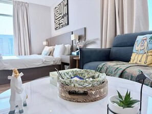A modern hotel room with a bed, a sofa, a coffee table with decorative items, and a wall art piece. - Best City View Studio / Heart of the city FNS1401O (Capital Governorate)