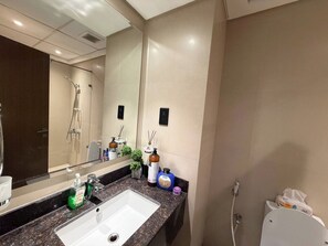 Ein modernes Badezimmer mit großem Spiegel, Waschbecken und Duschbereich.