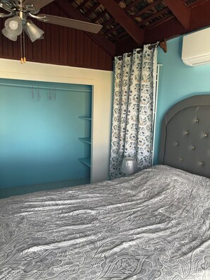 A bedroom with a bed, a ceiling fan, a window with curtains, and a wall-mounted air conditioner. - Peaceful, private 2-bedroom house with exclusive pool in Montego Bay (Montego Bay)