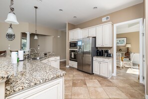 A modern kitchen with granite countertops, stainless steel appliances, and white cabinetry. - Coastal Fun at Bayside Resort | Near the Beach (Selbyville)