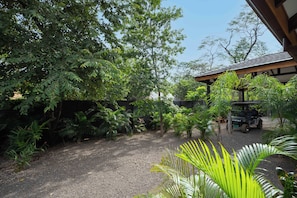 A garden with various plants and a vehicle parked on a gravel path. - Casa Moana l Luxury Balinese Villa- AC-Golf Cart (Playa Avellanas)
