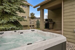 Ein Whirlpool mit einer Terrassenanlage, einem Grill und Blick auf benachbarte Gebäude.
