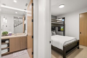 Een moderne slaapkamer met een stapelbed, een grote spiegel, een wastafel en uitzicht op de omgeving.