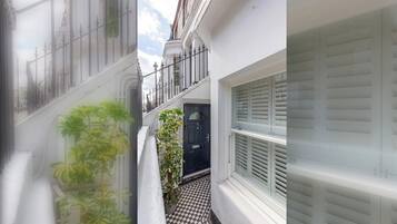 A narrow alleyway with a black door, a checkered floor, and a white wall with a window.