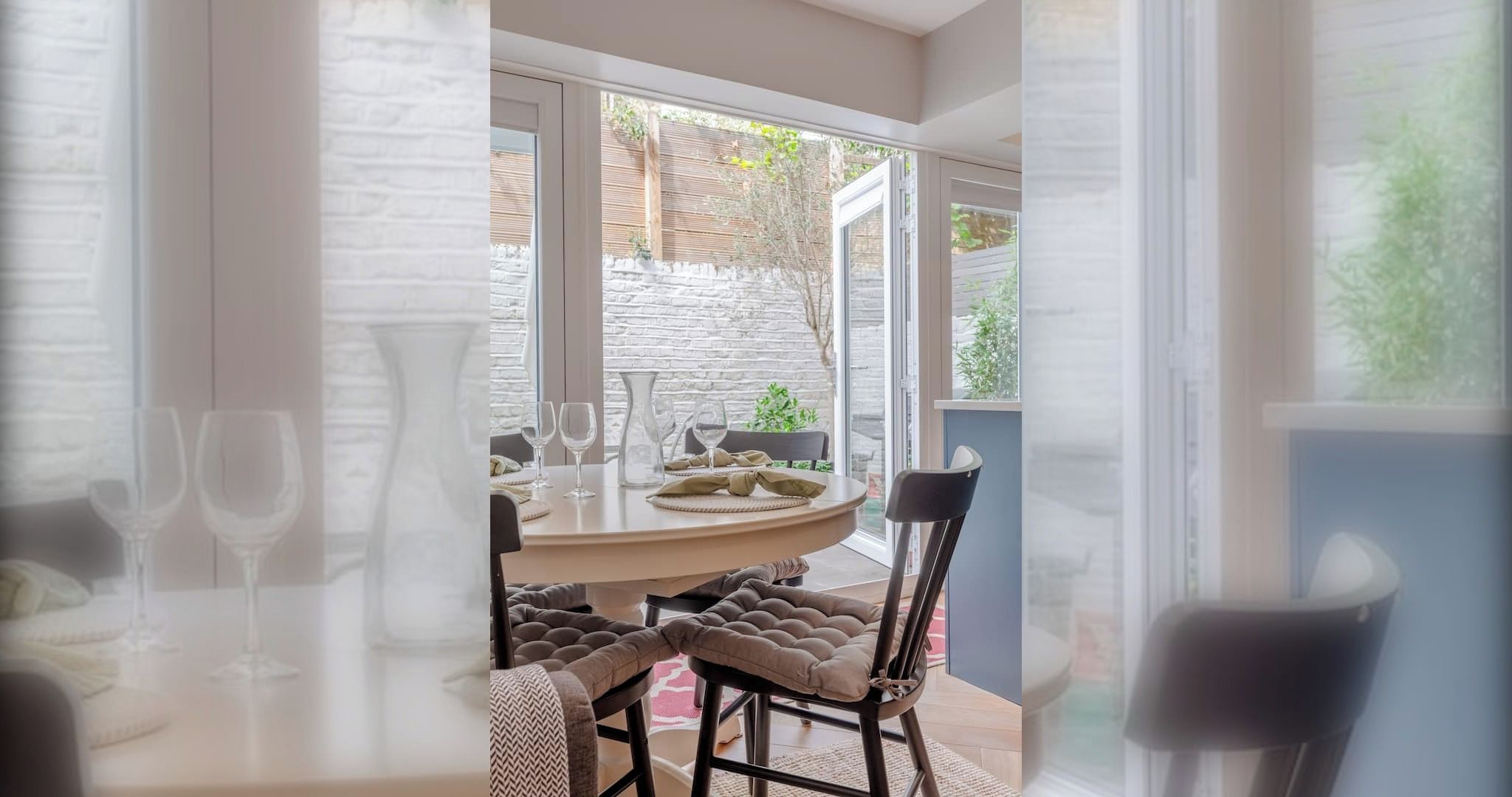 A dining area with a round table, chairs, and wine glasses.