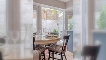 A dining area with a round table, chairs, and wine glasses.