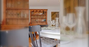 A dining area with a wooden buffet, a table set with glassware, and a chair. - Cosy stylish 1 bed flat in Fulham w patio (London)