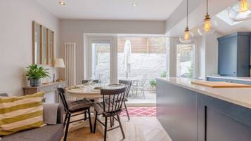 A modern kitchen with a dining area, large windows, and a view of the outdoors.