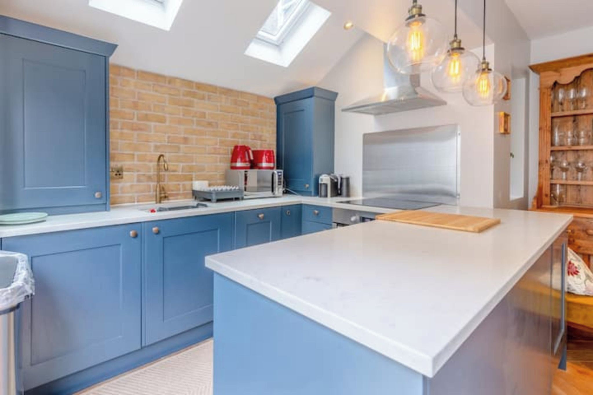 A modern kitchen with blue cabinets, a central island, and a skylight.