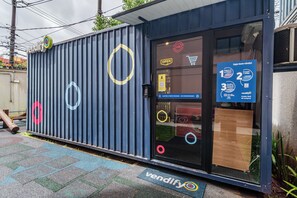 Un pequeño edificio de una planta con fachada azul, puerta de vidrio y un cartel que indica que está abierto.