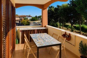 Ein Balkon mit Tisch und Stühlen, einem Blumentopf und Blick auf die Umgebung.