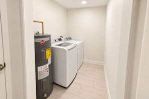 A laundry room with a large water heater, a washing machine, and a dryer. - Two Private Jacksonville Studios Near Hospitals (Jacksonville)