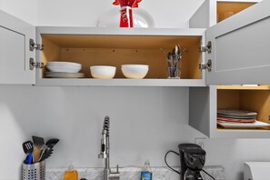 A kitchen with white cabinets, a sink, and various utensils. - Two Private Jacksonville Studios Near Hospitals (Jacksonville)