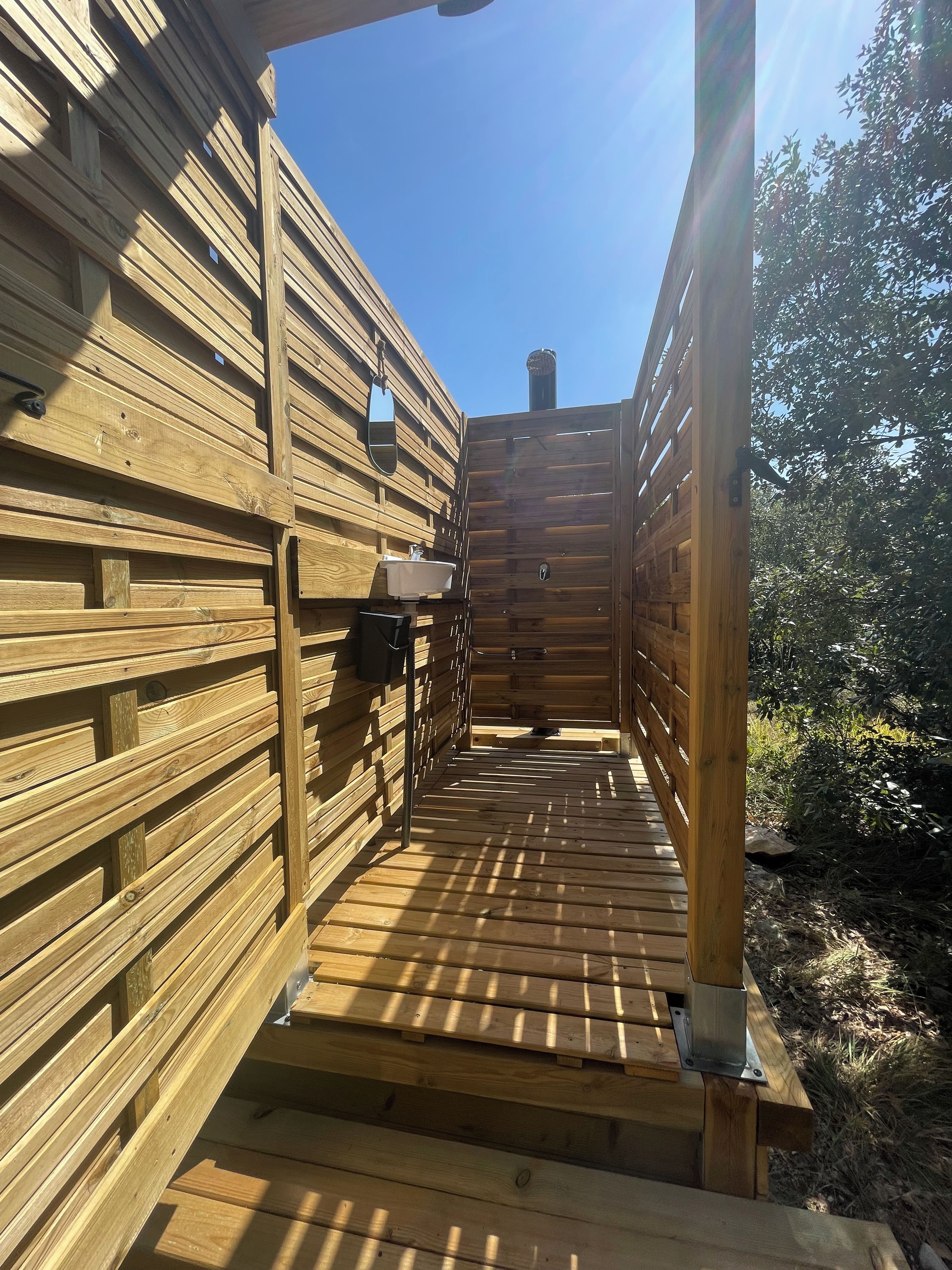A wooden outdoor deck leading to a building with a wooden exterior and a metal door.