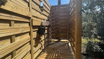 A wooden outdoor deck leading to a building with a wooden exterior and a metal door.