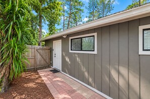 A single-story building with a grey exterior, a wooden fence, and a paved walkway. - Bright Jacksonville Studio Near Hospitals (Jacksonville)