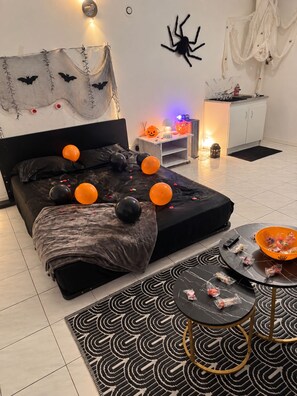 A bedroom with a bed, a nightstand, a lamp, a bowl of snacks, and Halloween decorations. - Cozy Downtown Perpignan Apartment (Perpignan)