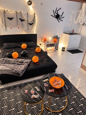 A bedroom with a bed, a nightstand, a table, and Halloween decorations. - Cozy Downtown Perpignan Apartment (Perpignan)