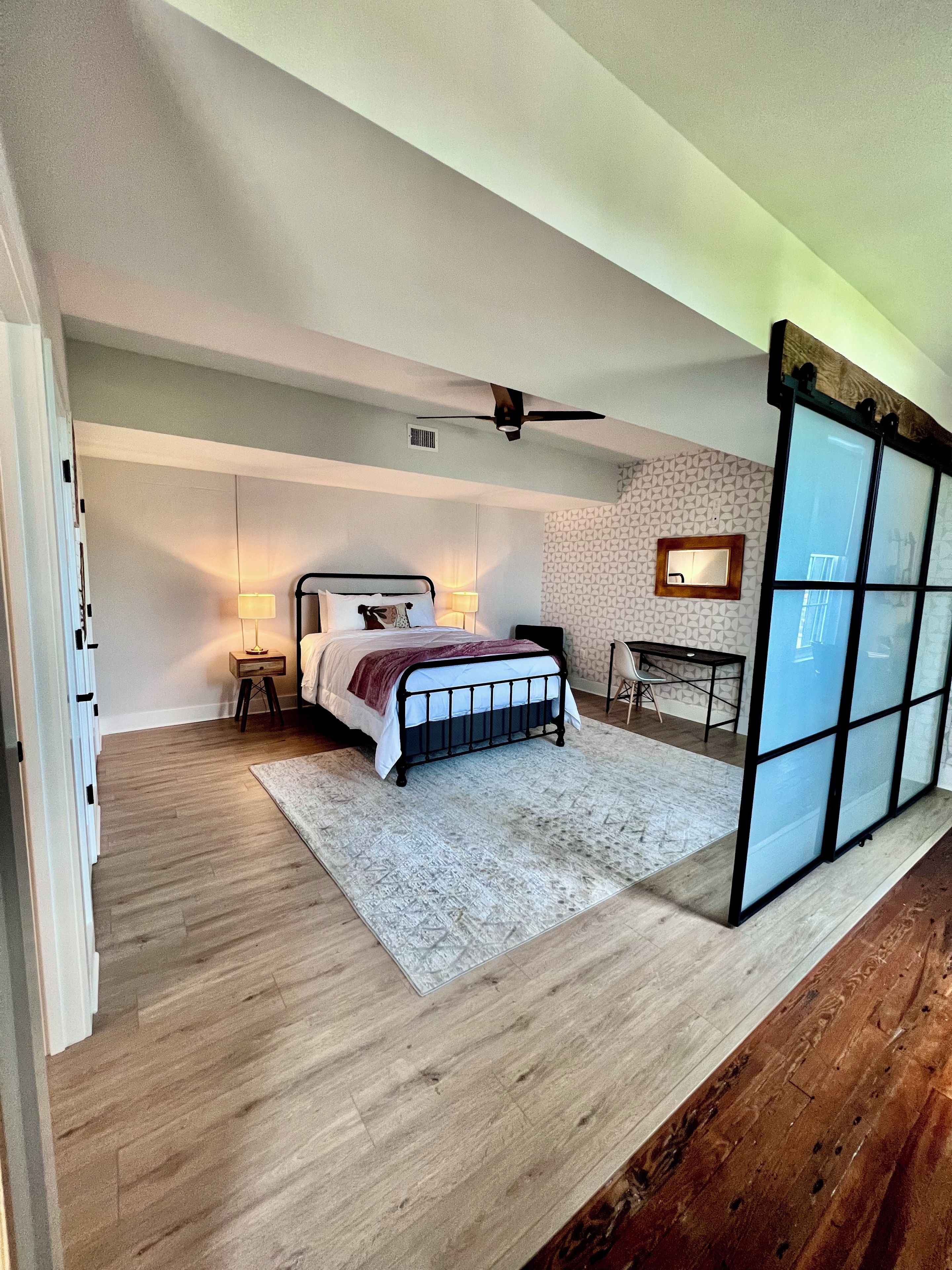 A bedroom with a bed, bedside tables, a desk, and a chair.