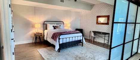 A bedroom with a bed, bedside tables, a desk, and a chair.