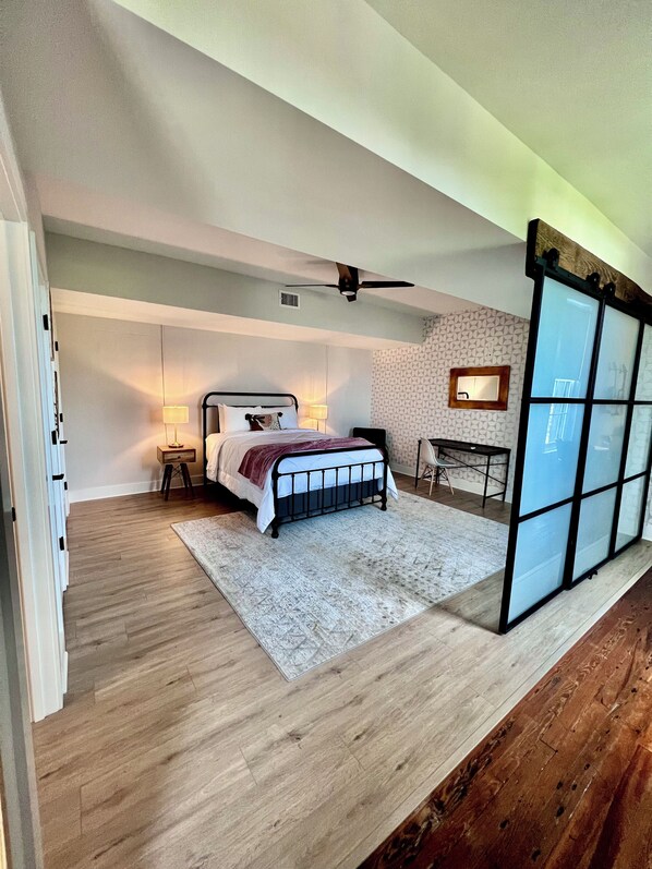 Un dormitorio con cama, mesitas de noche, escritorio y silla.