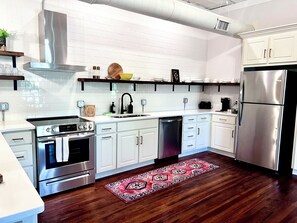 Una cocina moderna con armarios blancos, electrodomésticos de acero inoxidable y una alfombra estampada.