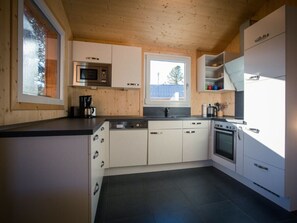 A modern kitchen with white cabinets, a microwave, a coffee maker, and a dishwasher. - Cabin in Turrach With Sauna and Terrace (Stadl-Predlitz)