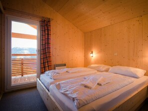 A wooden room with a bed, a window with curtains, and a view of the outdoors. - Cabin in Turrach With Sauna and Terrace (Stadl-Predlitz)