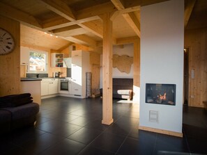 A modern interior with a kitchen, dining area, and a fireplace. - Cabin in Turrach With Sauna and Terrace (Stadl-Predlitz)