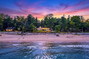 A beachfront property with a large house, a stone wall, and a beach. - Private Beach | Game Room | Near Kohler-Andrae (Sheboygan)