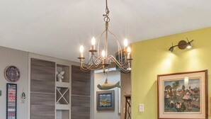 Uma sala de jantar com mesa de madeira, cadeiras cor turquesa e um lustre.