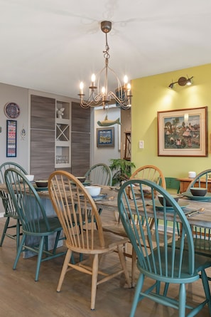 A dining area with a wooden table, teal chairs, and a chandelier. - Private Beach | Game Room | Near Kohler-Andrae (Sheboygan)