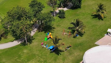 Vue aérienne d’un parc avec des jeux pour enfants, des palmiers et un chemin pavé.
