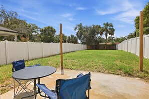 Un jardin avec une table et des chaises de patio, une clôture en bois et une pelouse.