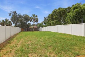 A fenced backyard with a grassy area and trees.
