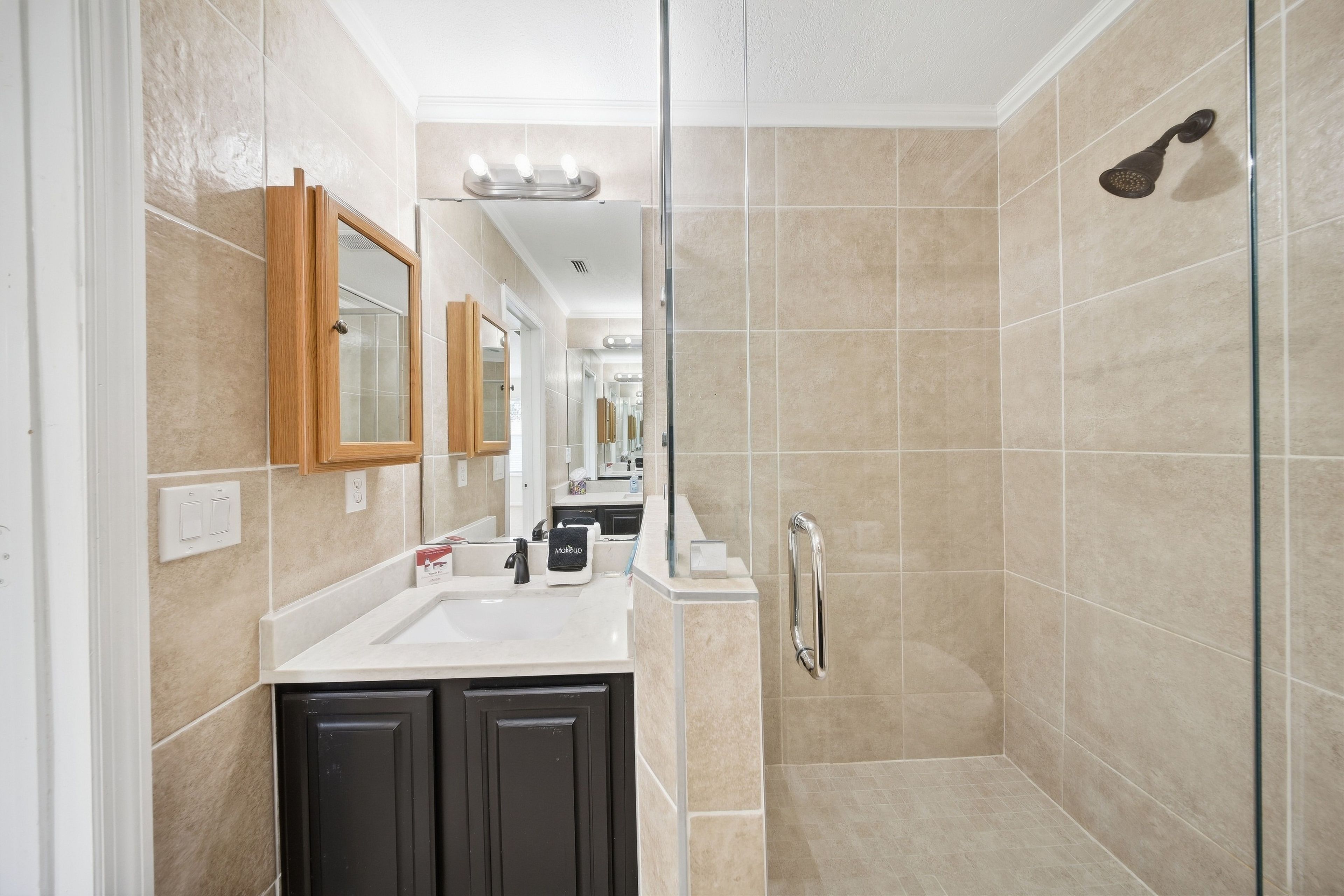 Un baño moderno con ducha, tocador y espejo.