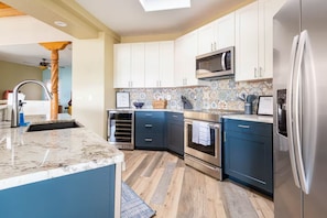 A modern kitchen with a marble countertop, stainless steel appliances, and blue cabinetry. - Sweeping Views, Arcade, Putting, Chef's Kitchen (Albuquerque)