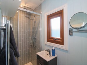 Ein Badezimmer mit Dusche, Waschbecken, Spiegel und Fenster.