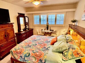 A bedroom with a bed, dresser, television, and a window with blinds. - Downtown Mid-Century Gem with Pool & Mountain Views, Heated Spa, Sleeps 4! (Palm Springs)