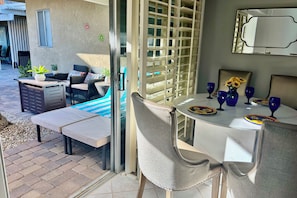 Uma área de pátio com mesa de jantar, cadeiras, sofá e uma piscina pequena.