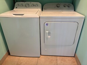A front view of a washer and dryer unit with control panels and a door with a sticker. - Downtown Mid-Century Gem with Pool & Mountain Views, Heated Spa, Sleeps 4! (Palm Springs)