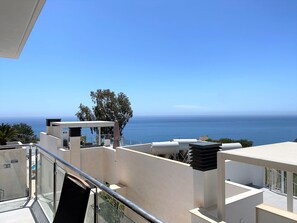 Ein Balkon mit freiem Blick auf das Meer, einer Glasufernung und einem modernen architektonischen Design.