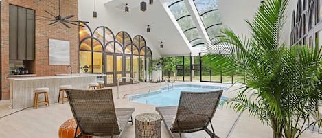 Zona junto a la piscina con sillones, bar y vistas a la piscina.