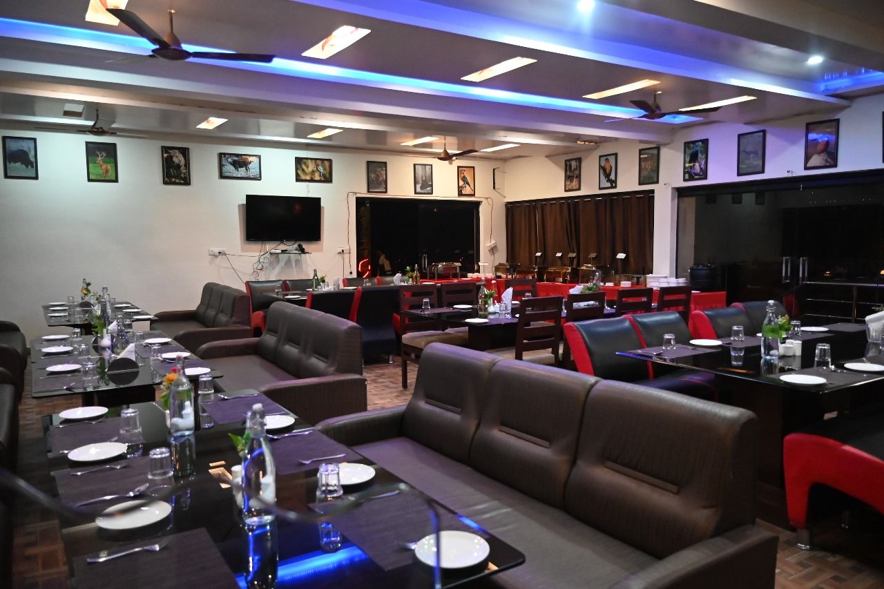 Een restaurant met verschillende eetgedeeltes, waaronder zitjes en tafels, met plafondventilatoren en inbouwverlichting.