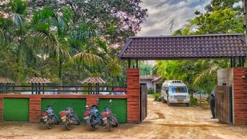 A gated entrance with a covered area, a dirt road, and parked motorcycles.