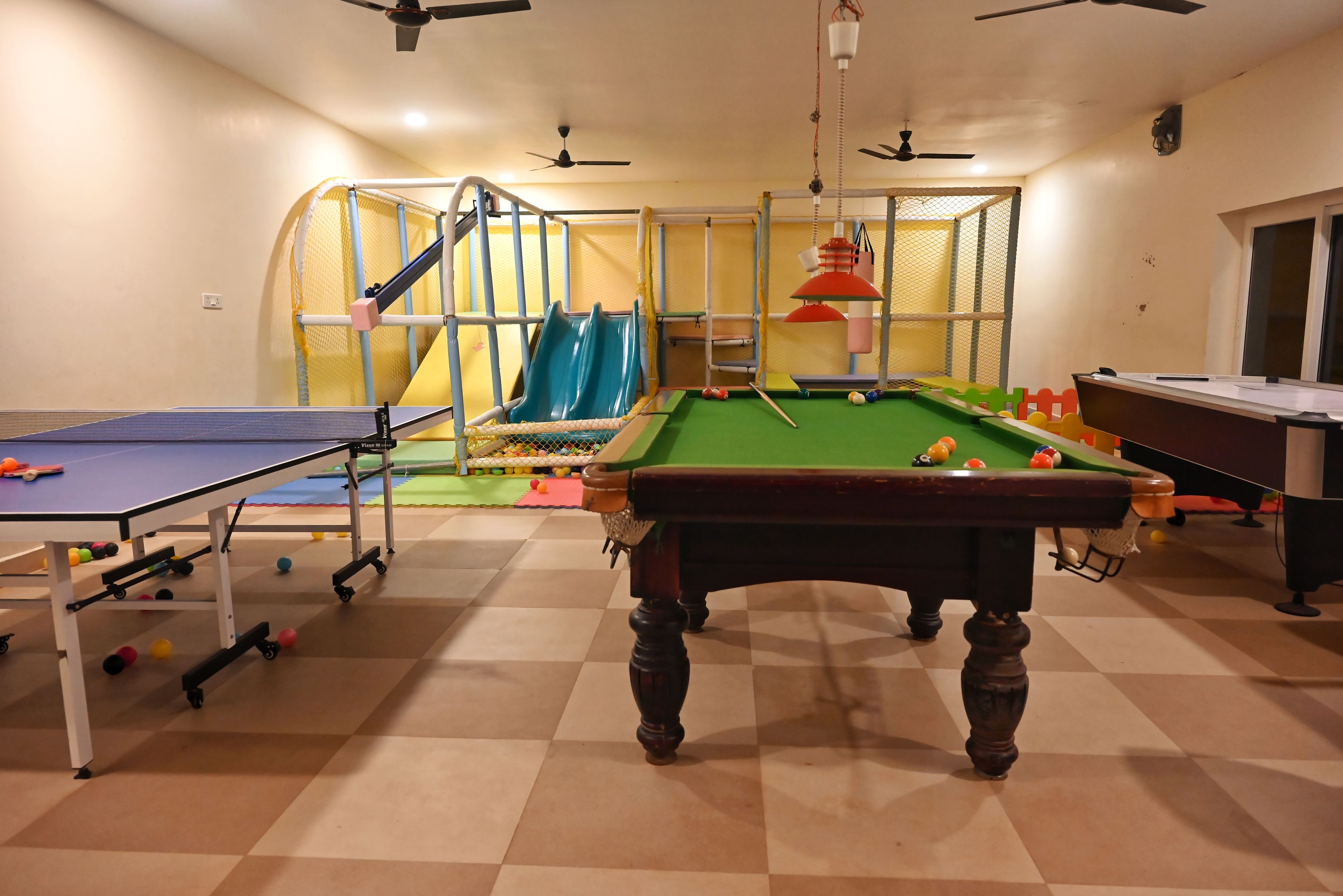 A recreational room with a pool table, a billiards table, and a children's play area with a slide.